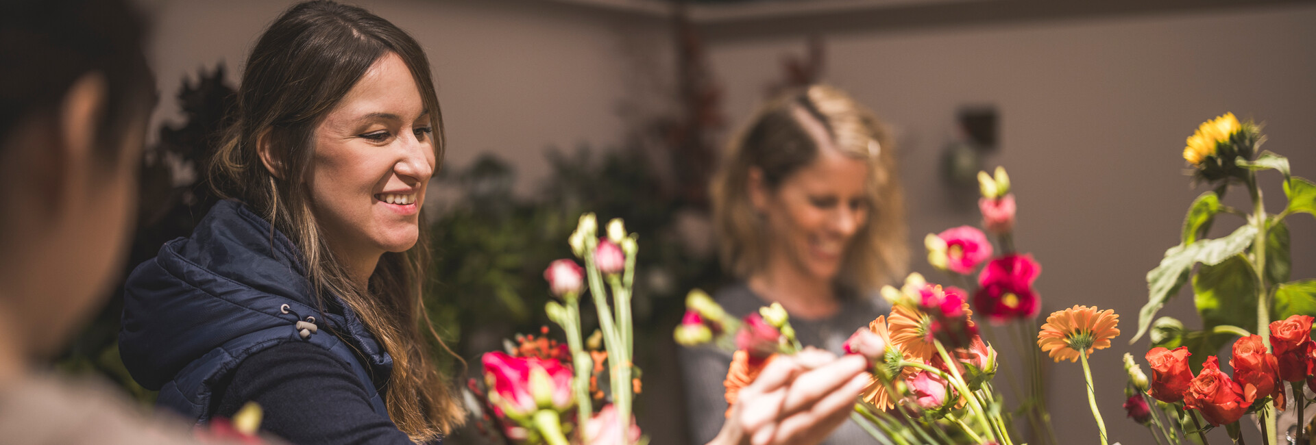 Zwei Mitarbeiter binden lachend Blumensträuße